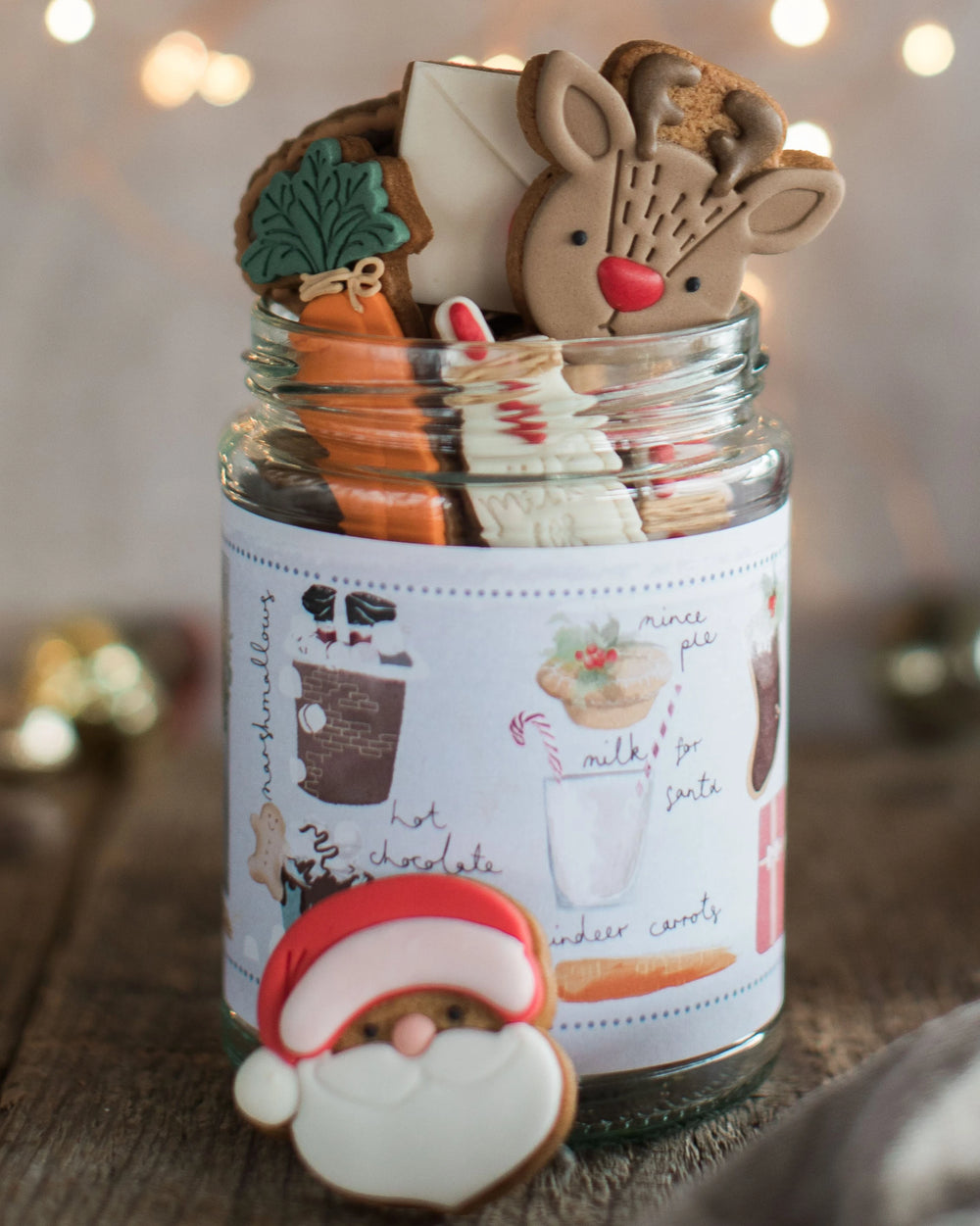 Honeywell Bakes Christmas Biscuits in a Jar -  A glass jar filled with assorted Christmas cookies, with a pretty hand illustrated label, designed as a Christmas Eve gift. Hand iced biscuits include a reindeer cookie, Santa, carrots for Rudolph and a glass of milk