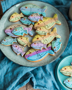 Honeywell Bakes Jar Of Fish - Colourful fish-shaped cookies on a ceramic plate with a blue cloth background