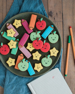 Honeywell Bakes Jar Of Smart Cookies - Decorative cookies shaped like apples, pencils, and stars on a plate with a wooden background.