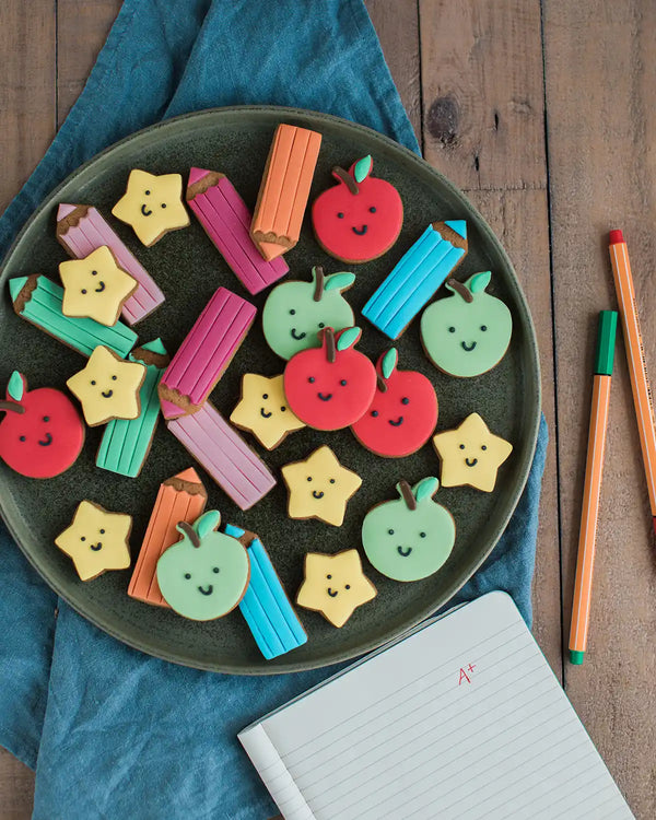 Honeywell Bakes Jar Of Smart Cookies - Decorative cookies shaped like apples, pencils, and stars on a plate with a wooden background.
