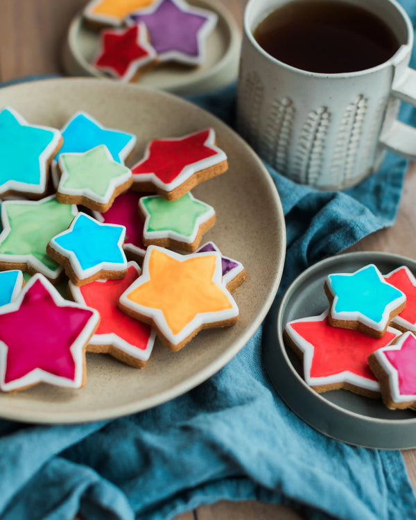 Honeywell Bakes Jar Of You’re A Star Biscuits - Colourful star-shaped cookies on a plate with a cup of coffee.