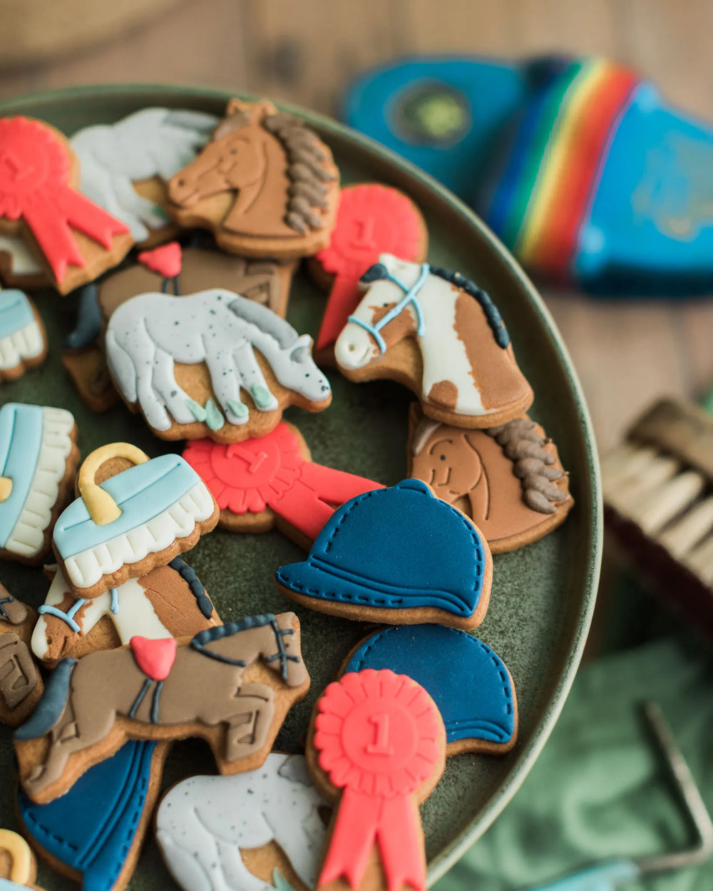Honeywell Bakes - Jar of Horse Biscuits - A glass jar labeled 'Honeywell Bakes Jar of Horse Biscuits' filled with horse-shaped and horse-themed handcrafted biscuits, with a small blue-and-white brush in front on a rustic tabletop.