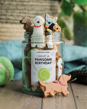 Personalised jar of dog-shaped biscuits from Honeywell Bakes, a cute and thoughtful gift for dog lovers with a custom label.