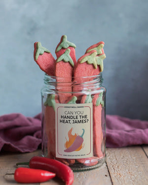 Honeywell Bakes Jar of Chilli Roulette Biscuits filled with red chilli-shaped cookies topped with green leafy stems, with a personalised label. Will you get a hot one?