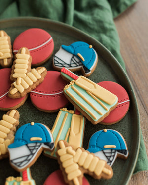 Honeywell Bakes Jar of Cricket Biscuit Gift - Decorative cookies shaped like cricket helmets, balls, and stumps on a green plate.