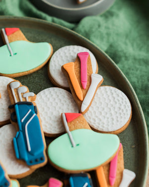 Honeywell Bakes Jar of Golf Biscuit Gift - Decorative cookies shaped like golf clubs and balls on a green plate.