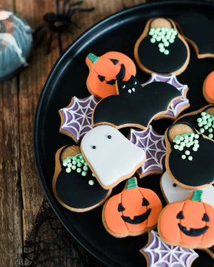 Honeywell Bakes Jar of Halloween Biscuits - Halloween-themed cookies on a black plate with spider webs and pumpkins.