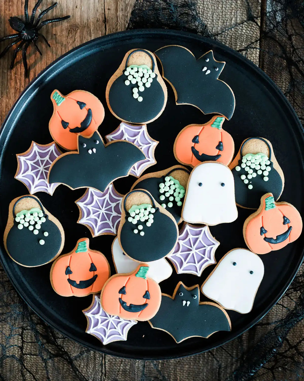 Honeywell Bakes Jar of Halloween Biscuits - Halloween-themed cookies on a black plate with spider webs and a spider in the background.