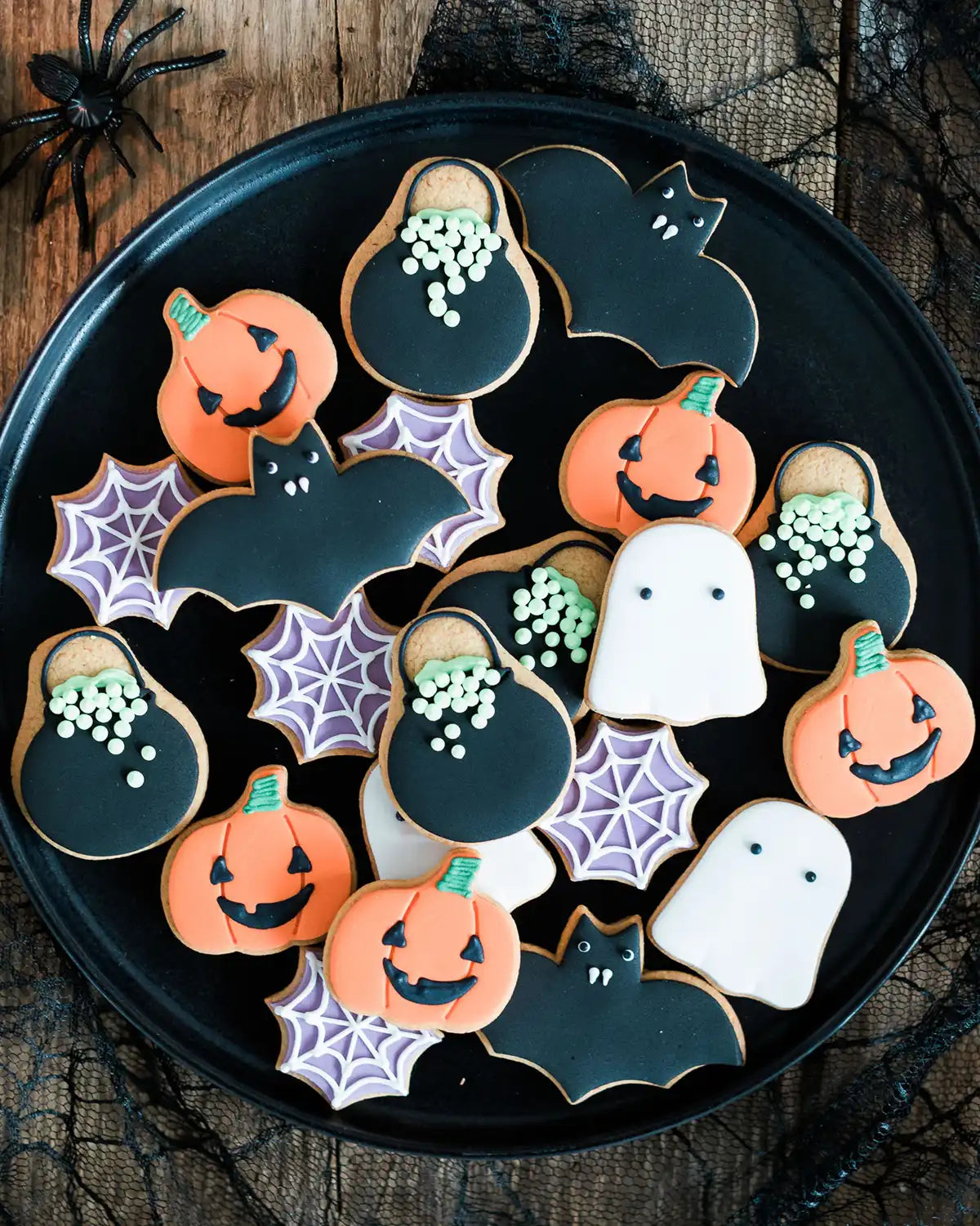 Honeywell Bakes Jar of Halloween Biscuits - Halloween-themed cookies on a black plate with spider webs and a spider in the background.