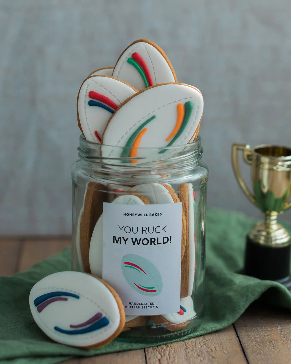 Honeywell Bakes Jar of Rugby Balls Biscuit Gift - Jar of cookies with a humorous label and a trophy in the background