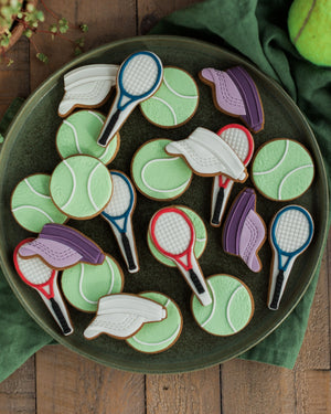Honeywell Bakes Jar of Tennis Biscuit Gift - Cookies shaped like tennis balls and rackets on a green plate with a wooden background.