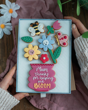 Honeywell Bakes Large Happy Biscuit Bloom Gift - Decorative biscuit set with floral and insect designs held by hands, featuring the text 'Mum thanks for helping me bloom'.