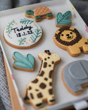 Honeywell Bakes Large Personalised Safari Biscuit Gift - Decorative cookies shaped like a turtle, lion, giraffe, and elephant on a white tray.