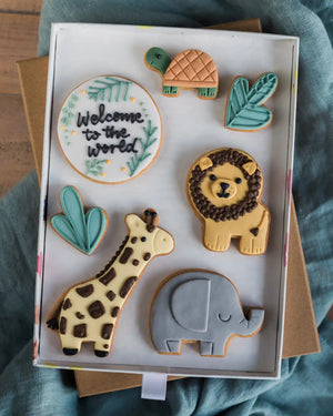 Honeywell Bakes Large Personalised Safari Biscuit Gift - Decorative cookies shaped like a lion, giraffe, elephant, and plants on a white tray.