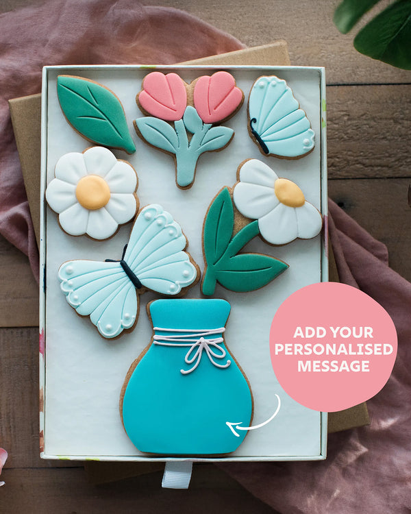 Honeywell Bakes Large Spring Biscuit Blooms - Decorative cookies shaped like flowers, leaves, and a vase in a box with a pink circle for personalisation.