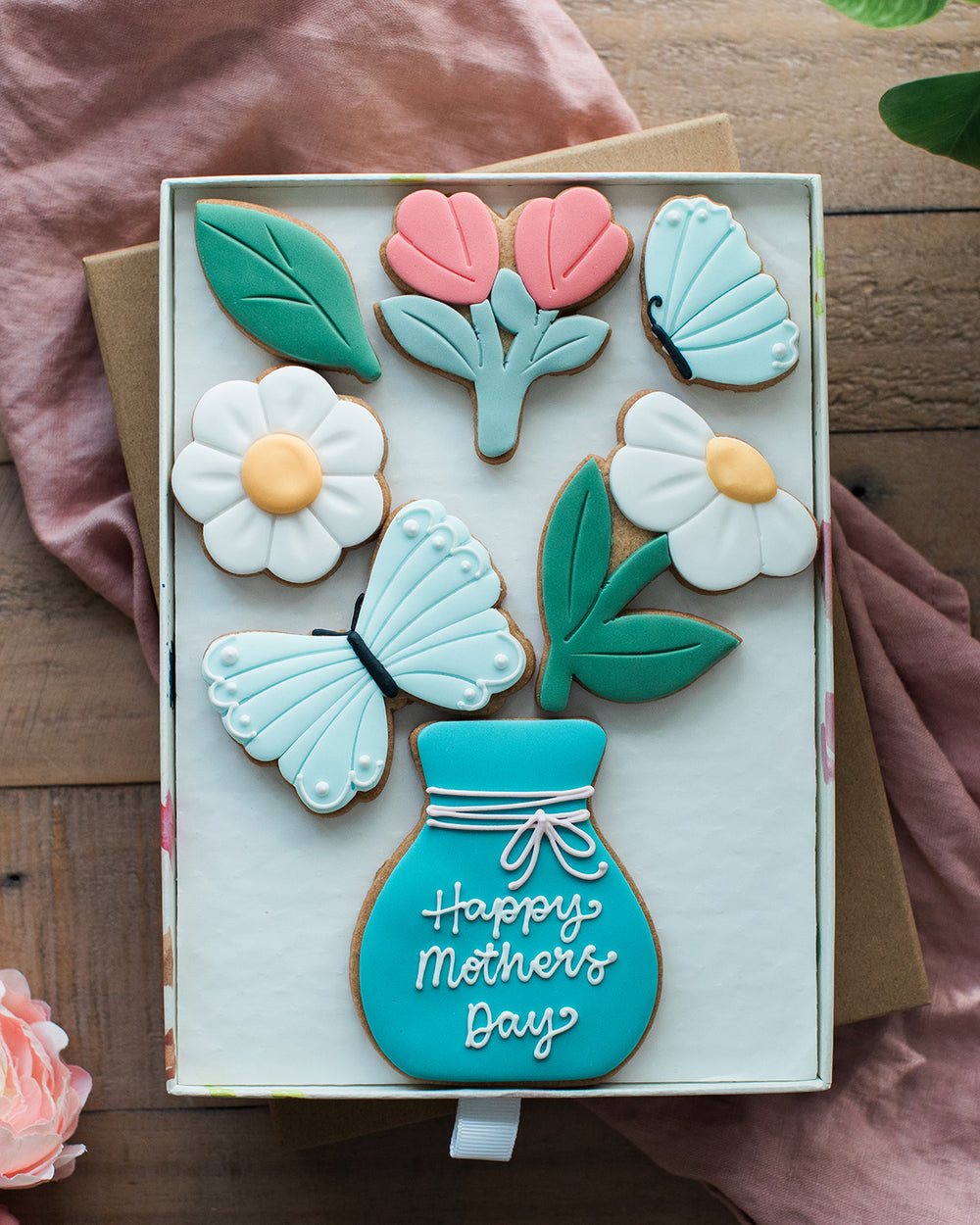 Honeywell Bakes Large Spring Biscuit Blooms - Decorative cookies shaped like flowers, leaves, and a vase in a box with a pink circle for personalisation.
