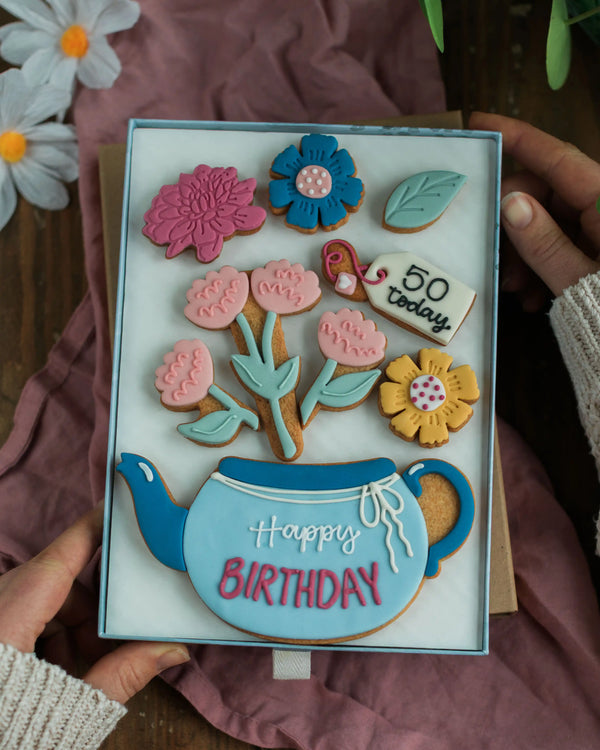 Honeywell Bakes Large Teapot Blooms Biscuit Gift - Handmade biscuit set with cookies shaped like flowers and a teapot, held by a person.