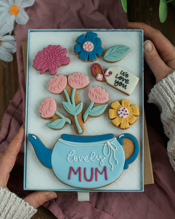 Honeywell Bakes Large Teapot Blooms Biscuit Gift - Decorative cookie box with floral designs and 'lovely MUM' text, held by hands.