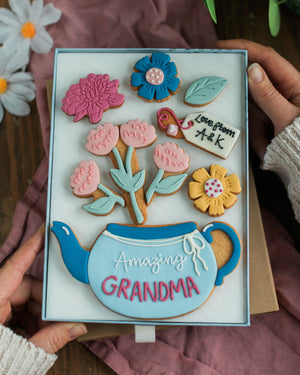 Honeywell Bakes Large Teapot Blooms Biscuit Gift - Decorative biscuit set with floral design and 'Amazing Grandma' text, held by hands.