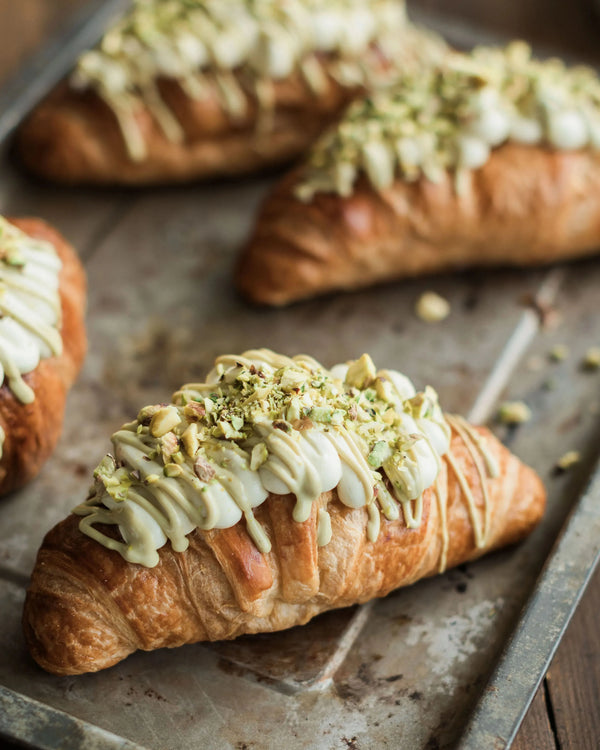 Honeywell Bakes Make Your Own Pistachio Croissant Baking Kit - Croissants with pistachio buttercream and green pistachio toppings on a baking tray.