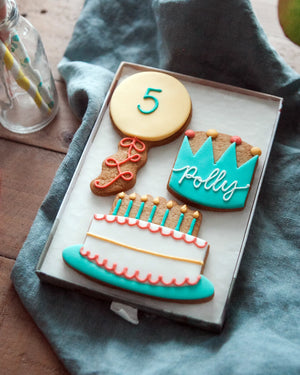 Honeywell Bakes Medium Birthday Party Biscuit Gift Decorative cookies shaped like a balloon with a number 5, a birthday cake, and crown with personalised name  on a blue cloth.