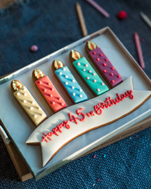 Honeywell Bakes Medium Personalised Birthday Candles Gift- Decorative birthday cookies shaped like candles on a blue textured background