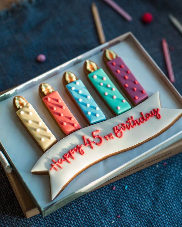 Honeywell Bakes Medium Personalised Birthday Candles Gift- Decorative birthday cookies shaped like candles on a blue textured background