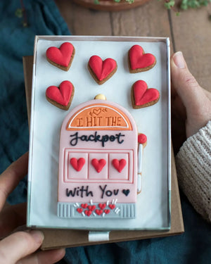  Honeywell Bakes Medium I Hit The Jackpot With You Biscuit Gift - Gift box with a pink slot machine cookie and red heart cookies, held by two hands.