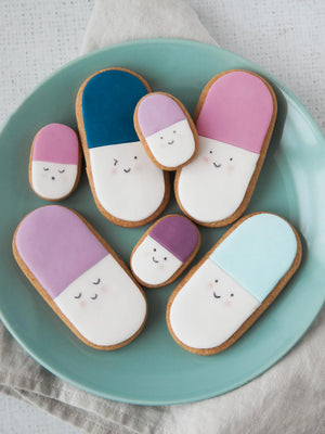 Honeywell Bakes Medium get well soon biscuit gift - Decorative cookies shaped like pill capsules on a teal plate.