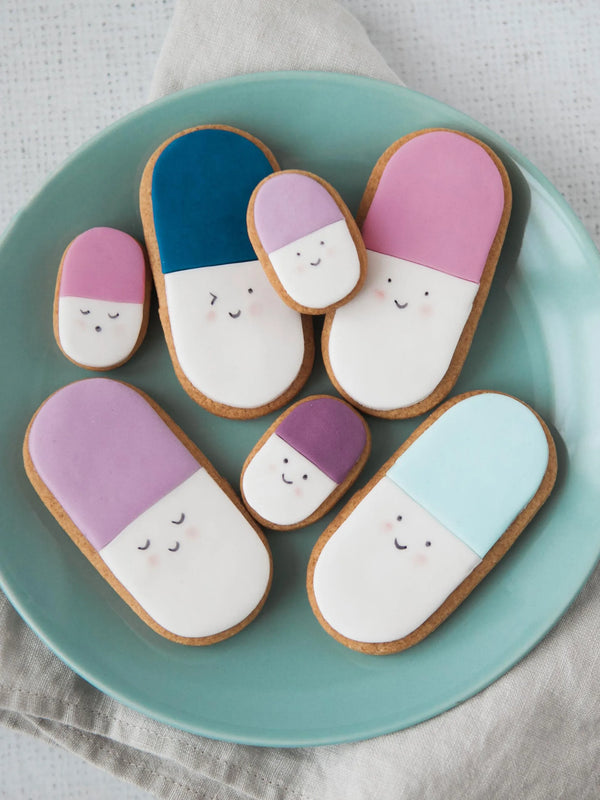 Honeywell Bakes Medium get well soon biscuit gift - Decorative cookies shaped like pill capsules on a teal plate.