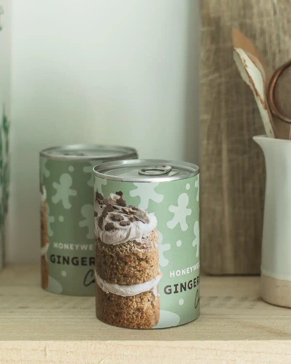Honeywell Bakes Mini Gingerbread Cake Kit - Two cans of ‘Honeywell Bakes' gingerbread cake on a wooden surface with a blurred background.