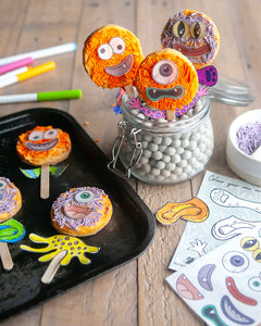Honeywell Bakes Monster Biscuit Pop Baking Kit - Colourful monster-themed cookies on sticks with activity card and decorations on a wooden table.