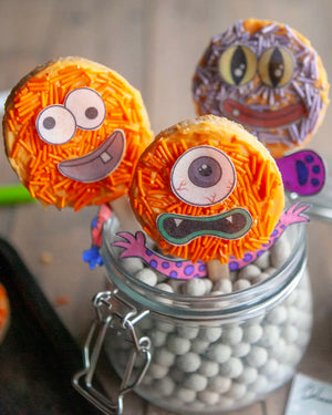 Honeywell Bakes Monster Biscuit Pop Baking Kit - Colourful monster-themed cookies on sticks in a jar on a wooden table.
