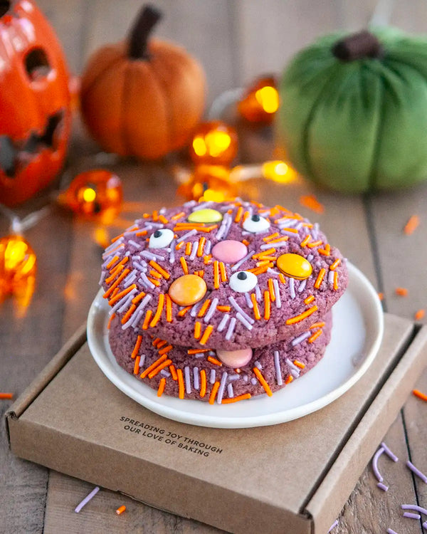 Honeywell Bakes Monster Cookie Kit - Halloween-themed cake with colourful sprinkles on a plate, surrounded by pumpkins and decorative lights.