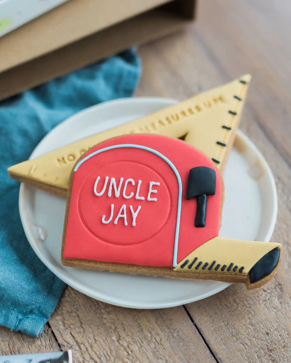 Honeywell Bakes No One Else Measures Up Biscuit Gift - Cookie shaped like a tape measure with 'UNCLE JAY' text on a white plate.