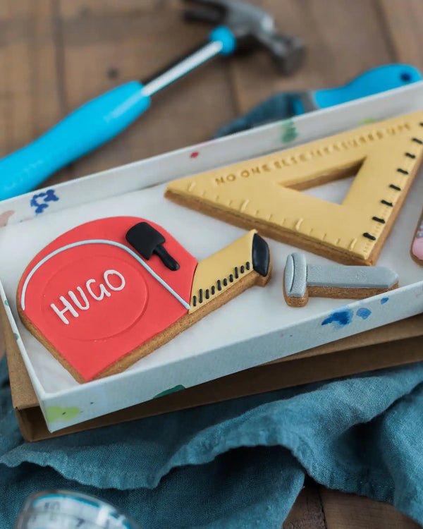 Honeywell Bakes No One Else Measures Up Biscuit Gift - Decorative cookies shaped like tools and measuring instruments on a wooden surface with a blue towel.