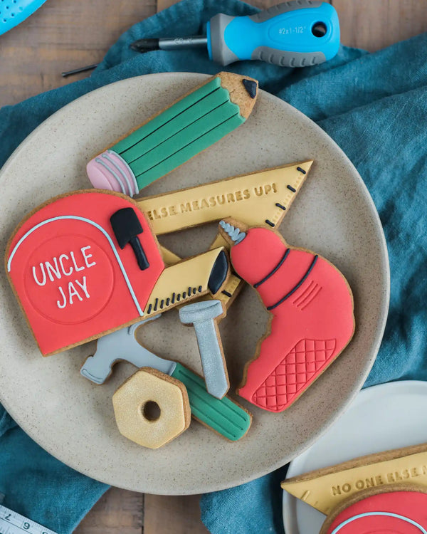 Honeywell Bakes No One Else Measures Up Biscuit Gift - Set of cookie cutters shaped like tools on a plate with a blue towel in the background.