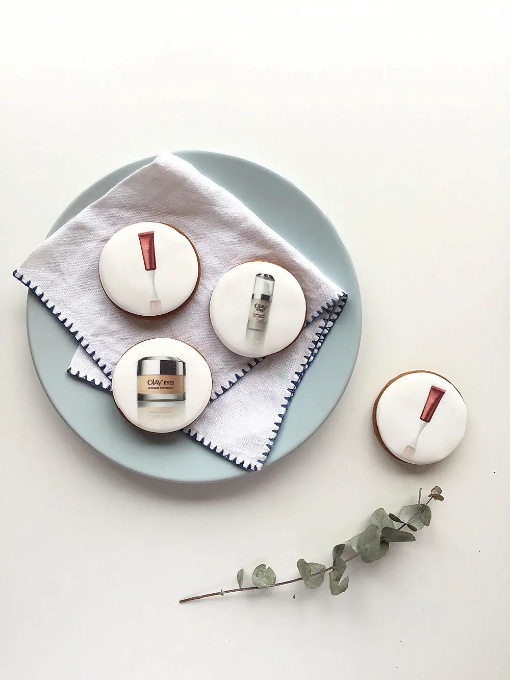 Biscuits with cosmetic products printed on the icing, on a plate with a white background
