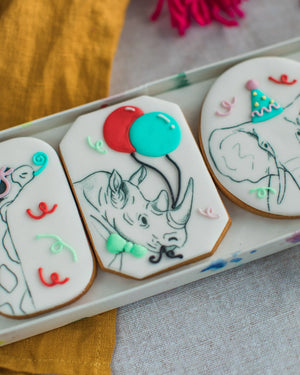Honeywell Bakes Party Animal Biscuit Gift - Decorative cookies with rhino illustrations and colourful accents on a white tray.