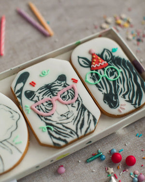 Honeywell Bakes Party Animal Biscuit Gift - Decorative cookies with zebra designs wearing glasses and a party hat on a tray.
