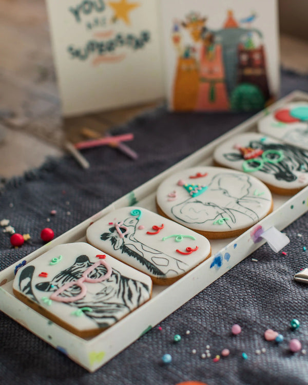 Honeywell Bakes Party Animal Biscuit Gift - Decorated cookies with zebra designs on a tray, with a colourful background.