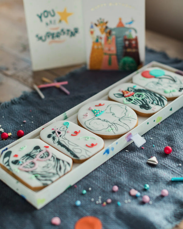 Honeywell Bakes Party Animal Biscuit Gift - Decorative cookies with animal designs on a tray, with a colourful card in the background.