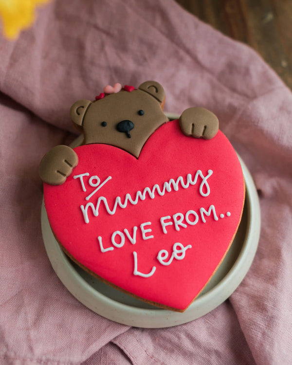 Honeywell Bakes Personalised Bear Hug Biscuit - large biscuit bear holding a heart with ’To Mummy, Love from Leo’ text.