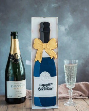 Honeywell Bakes Personalised Champagne Biscuit Bottle - Navy - A hand iced large biscuit in the shape of a champagne bottle next to a celebration glass