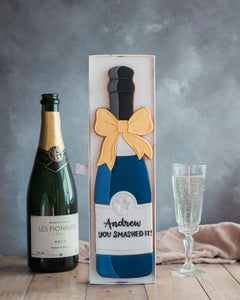 Honeywell Bakes Personalised Champagne Biscuit Bottle - Navy - A hand iced large biscuit in the shape of a champagne bottle next to a celebration glass