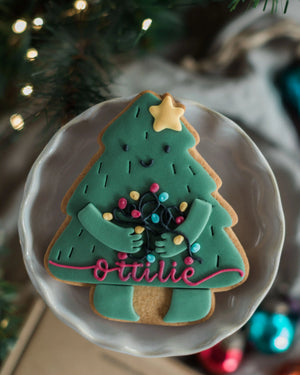 Personalised Christmas Tree Biscuit - A decorated Christmas tree-shaped sugar cookie with a yellow star topper, colourful icing lights, and a personalised name.