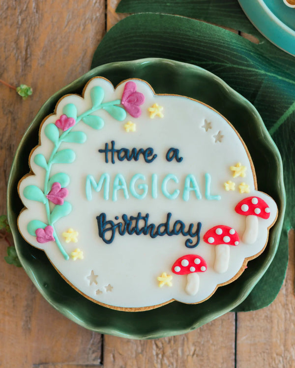 Honeywell Bakes Personalised Fairy Circle Biscuit - Decorative cookie with 'Have a Magical Birthday' text on a green plate.