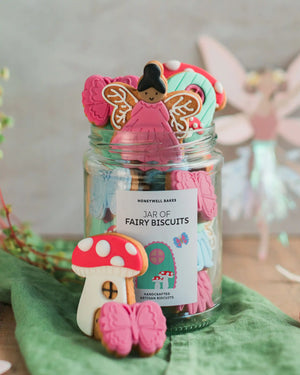 Honeywell Bakes Personalised Fairy Garden Biscuit Jar - Jar of fairy-themed cookies with a decorative label on a green surface.