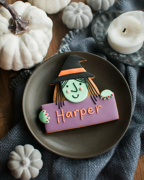 Honeywell Bakes Personalised Halloween Biscuit Witch - Halloween-themed cookie with a witch design and 'Harper' text, surrounded by pumpkins and candles.
