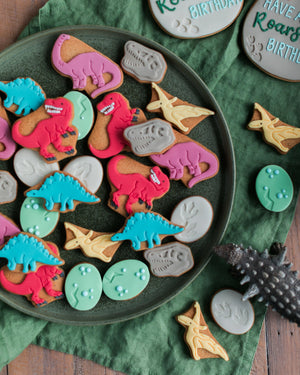 Honeywell Bakes Personalised Jar of Dinosaur Biscuits - Dinosaur-shaped cookies on a plate with a green napkin and wooden surface.